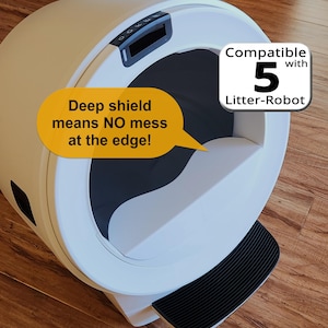 Op de afbeelding: Een witte en zwarte automatische kattenbak met de tekst "Deep shield means NO mess at the edge!" en "Compatible with 5 Litter-Robot". De kattenbak heeft een zwarte opstap en een bedieningspaneel.