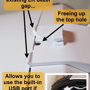 May include: A white plastic component with text that reads "Latches onto the existing LR bezel gap...", "Freeing up the top hole", and "Allows you to use the built-in USB port if desired". A small inset image shows a USB port.