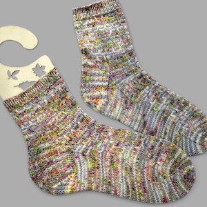 May include: A pair of colourful, hand-knitted socks with a speckled pattern in shades of grey, brown, yellow, and pink.