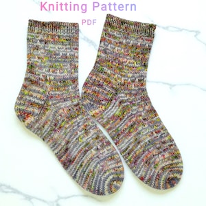 Könnte beinhalten: Ein Paar handgestrickte Socken mit einem gesprenkelten Muster in Grau-, Braun- und leuchtenden Farbtönen. Die Socken werden auf einer weißen Oberfläche präsentiert. Der Text "Knitting Pattern PDF" ist oben im Bild zu sehen.