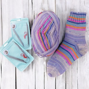 May include: A collection of knitting supplies, including a ball of purple and multicolored yarn, a knitted sock with stripes, and two packages of knitting needles with stitch markers. The items are arranged on a white wooden surface.