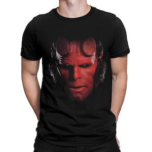 May include: Black t-shirt featuring a red and black graphic of the character Hellboy's face.