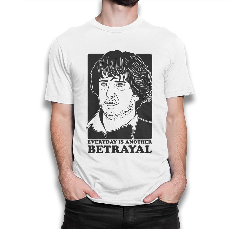 Puede incluir: Camiseta blanca con una ilustraci&oacute;n en blanco y negro de la cara de un hombre y el texto "EVERYDAY IS ANOTHER BETRAYAL".