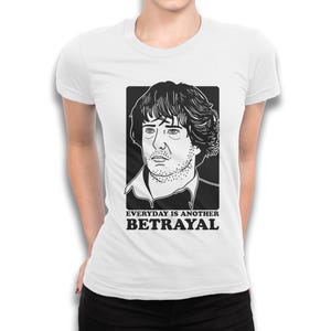 Puede incluir: Camiseta blanca con una ilustraci&oacute;n en blanco y negro de la cara de un hombre y el texto "EVERYDAY IS ANOTHER BETRAYAL".