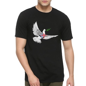 Könnte beinhalten: Ein schwarzes T-Shirt mit einer weißen Taube, die einen Olivenzweig und ein rotes Ziel auf der Brust trägt.