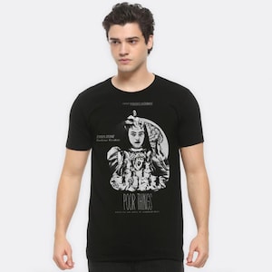 May include: Black t-shirt with a white graphic of Emma Stone from the movie "Poor Things". The graphic includes the movie title and the text "A film by Yorgos Lanthimos".