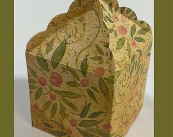 May include: A small, square-shaped paper box with a scalloped top closure. The box features a tan, speckled background decorated with a repeating pattern of green leaves, thin swirling vines, and small pink berries or flower buds.