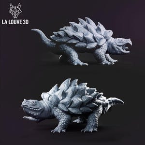 May include: Two detailed, gray 3D-printed Ankylosaurus models. The prehistoric creatures have textured skin, spiked armor, and open mouths. The logo "LA LOUVE 3D" is in the upper left corner. The models are on a dark background.