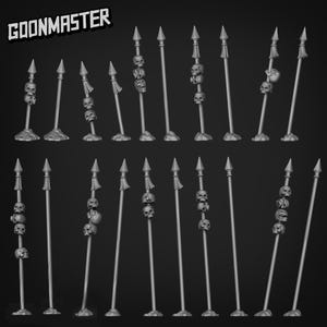Puede incluir: Una colección de lanzas grises en miniatura, cada una con una punta y elementos decorativos. Algunas lanzas presentan calaveras y borlas. El texto "GOONMASTER" se muestra en la esquina superior izquierda.
