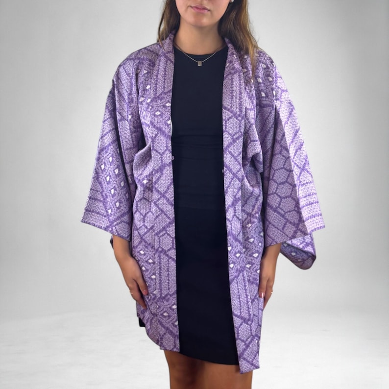 Puede incluir: Una chaqueta estilo kimono lavanda con un patr&oacute;n geom&eacute;trico. La chaqueta abierta tiene mangas anchas y un ajuste relajado. El patr&oacute;n incluye formas de diamante y hexagonales en un tono m&aacute;s claro de lavanda y blanco.