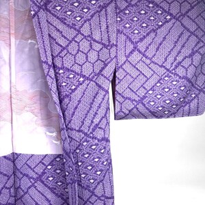 Puede incluir: Primer plano de un kimono morado con un patr&oacute;n geom&eacute;trico. El kimono tiene un dise&ntilde;o blanco y rosa en el lado izquierdo, con un paisaje con nubes y animales. El patr&oacute;n principal es un dise&ntilde;o repetitivo de diamantes y hex&aacute;gonos.
