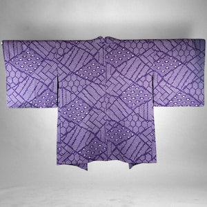 Puede incluir: Un kimono morado con un patr&oacute;n geom&eacute;trico. El kimono presenta un dise&ntilde;o repetitivo de rect&aacute;ngulos, hex&aacute;gonos y rombos. La tela tiene una apariencia texturizada, y la est&eacute;tica general es tradicional y elegante.