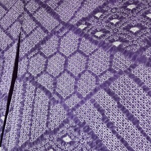 Puede incluir: Primer plano de una tela morada con un patr&oacute;n geom&eacute;trico. El dise&ntilde;o presenta una combinaci&oacute;n de formas de diamante y hexagonales, con una textura punteada. La tela tiene una abertura en el medio, revelando un interior m&aacute;s oscuro.