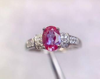 Può includere: Un anello d'argento con una grande pietra ovale rossa circondata da piccole pietre bianche.