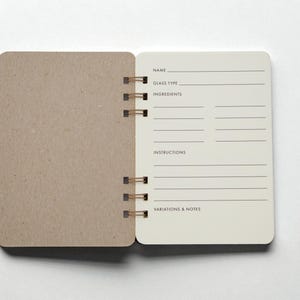 Open Mix Manual cocktail recipe journal with structured ivory colored drink recipe pages for name, glass type, ingredients, instructions, and notes — handmade bar notebook