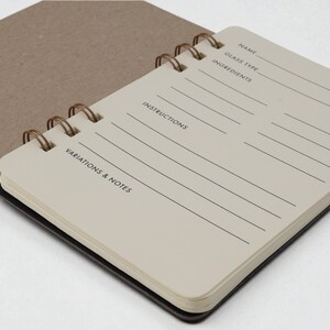 Inside page of Mix Manual cocktail recipe journal showing guided ivory colored recipe pages with sections for name, glass type, ingredients, instructions, and notes — mixology notebook