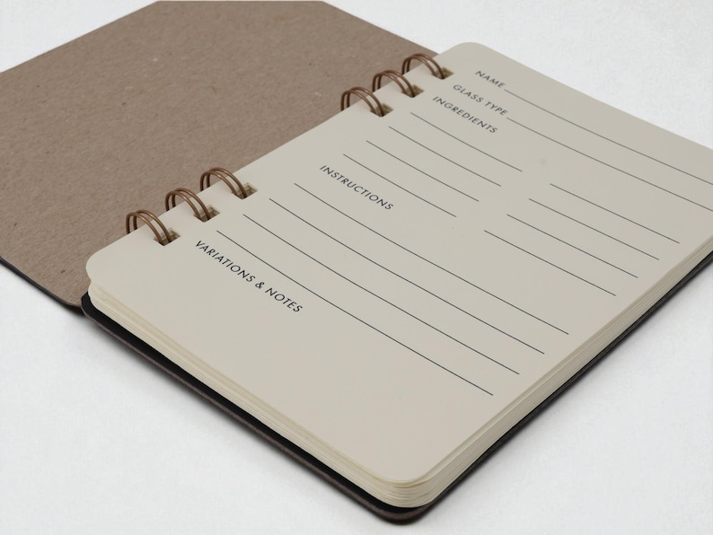 Inside page of Mix Manual cocktail recipe journal showing guided ivory colored recipe pages with sections for name, glass type, ingredients, instructions, and notes — mixology notebook