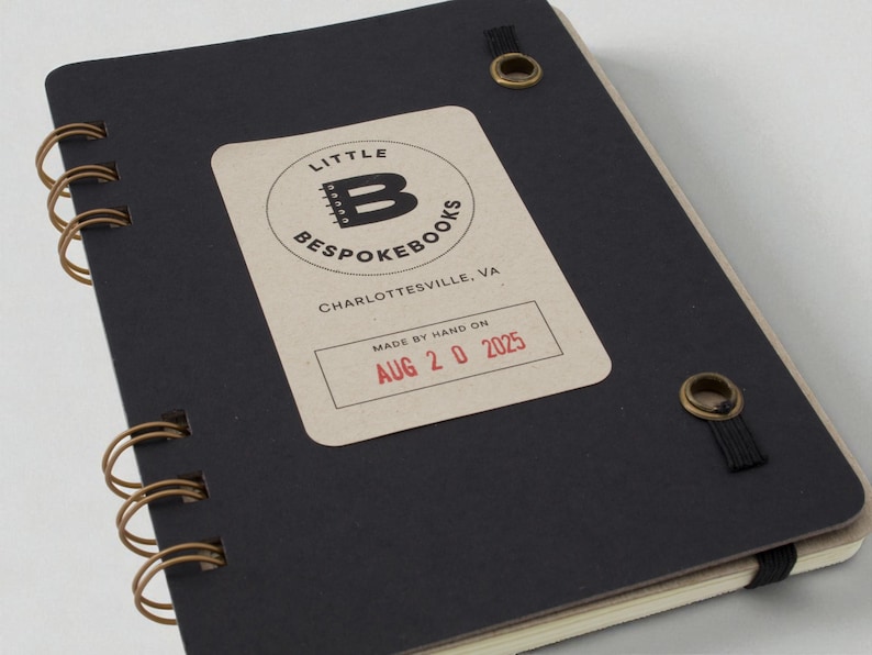 Mix Manual cocktail recipe journal with black chipboard interior cover, label stamped with date made, bronze grommets securing elastic band, and wire binding — handmade bar notebook for cocktails and mixology