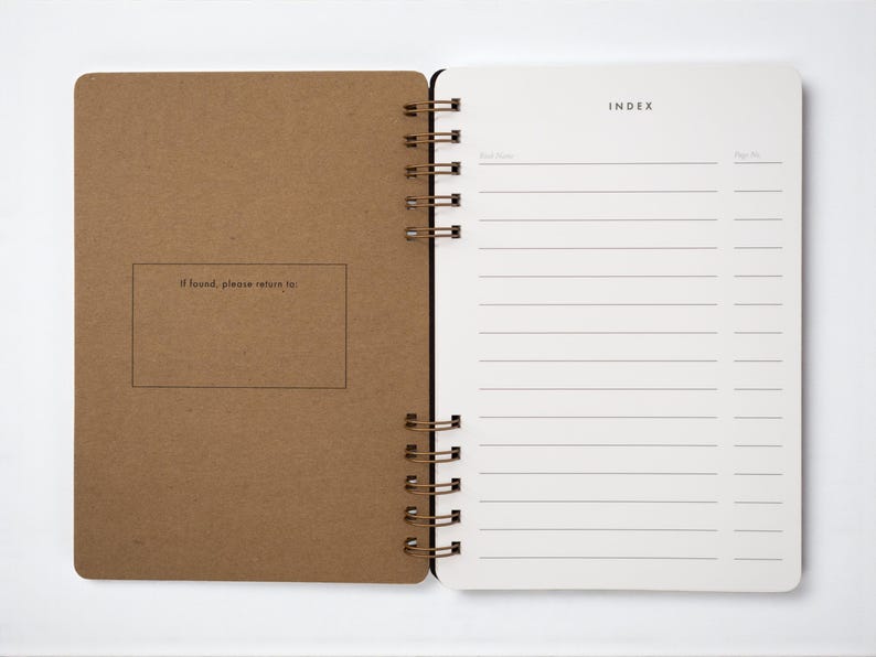 Inside pages of handmade book journal open to the index spread. Left interior cover of journal includes an “If found, please return to” box. Right-hand page has lined index to record book titles and page numbers. Bound with antique brass wire, archival-quality ultrawhite paper.