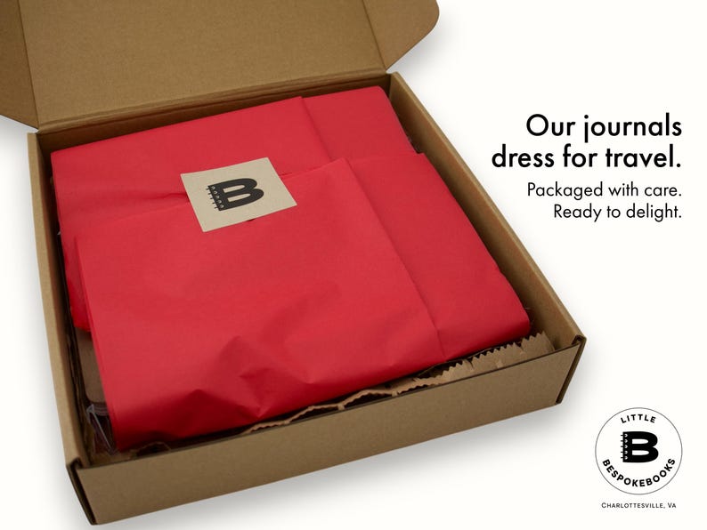 Little Bespokebooks packaging presentation. Open kraft shipping box lined with red tissue paper, sealed with a kraft sticker featuring the Little Bespokebooks “B” logo. Text in the image reads: Our journals dress for travel. Packaged with care. Ready to delight. Logo mark and Charlottesville, Virginia location also visible in the corner.