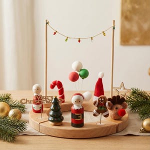 Può includere: Un centrotavola natalizio in legno con statuine festive come Babbo Natale, una renna e un omino di pan di zenzero. La composizione include un bastoncino di zucchero, un albero di Natale e palloncini, il tutto su una base di legno.