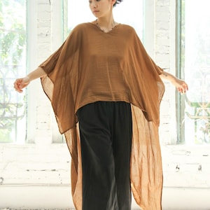 May include: A brown, flowing, high-low top with a v-neck and long sleeves. The top is paired with black wide-leg pants.