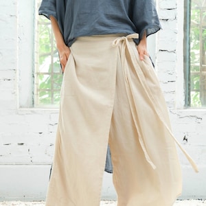 May include: A beige wrap skirt with a long tie that can be tied at the waist. The skirt is made of a lightweight fabric and has a relaxed fit.