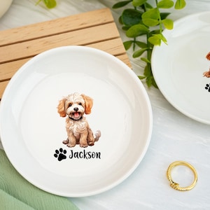 Puede incluir: Cuenco blanco de cerámica para mascotas con una ilustración en acuarela de un perro esponjoso, marrón claro y blanco. El nombre del perro, "Jackson", está impreso debajo en negro, junto con una huella de pata. Un anillo dorado está en el fondo.