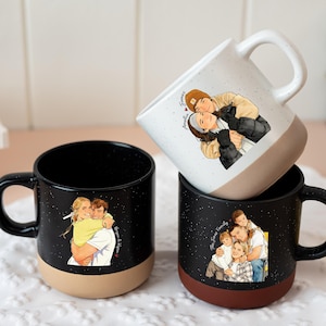 May include: Three ceramic mugs with black speckled exteriors and contrasting colored bases. Each mug features a custom illustration of people hugging. One mug is white with a tan base. The other two mugs have black handles.