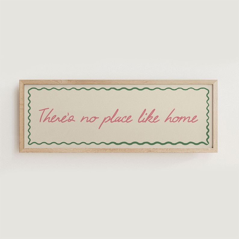 May include: A rectangular wooden framed sign with the text "There's no place like home" in pink script. The text is inside a cream-colored rectangle with a green wavy border.