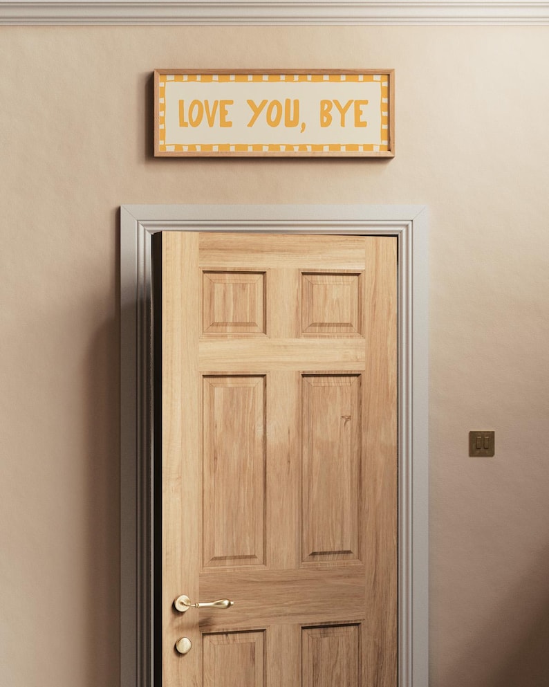 May include: A wooden door with a brass door handle and a framed sign above it that reads "LOVE YOU, BYE" in yellow letters on a white background.