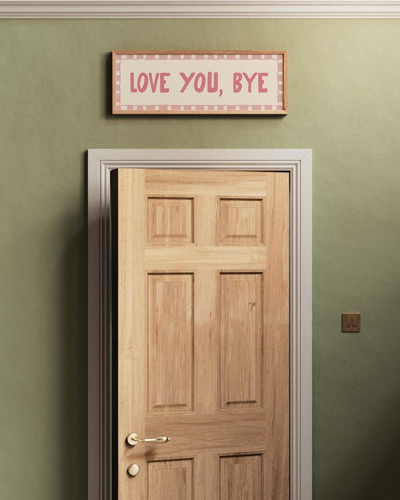May include: A wooden door with a gold door handle and a sign above it that reads "LOVE YOU, BYE" in pink letters on a white background with a pink and white checkered border.