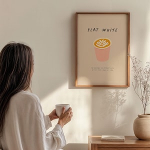 May include: A framed print with the text "FLAT WHITE" and a stylized illustration of a coffee cup with a latte art design. The text below the illustration reads "113 degrees espresso strained with a thin layer of foam."