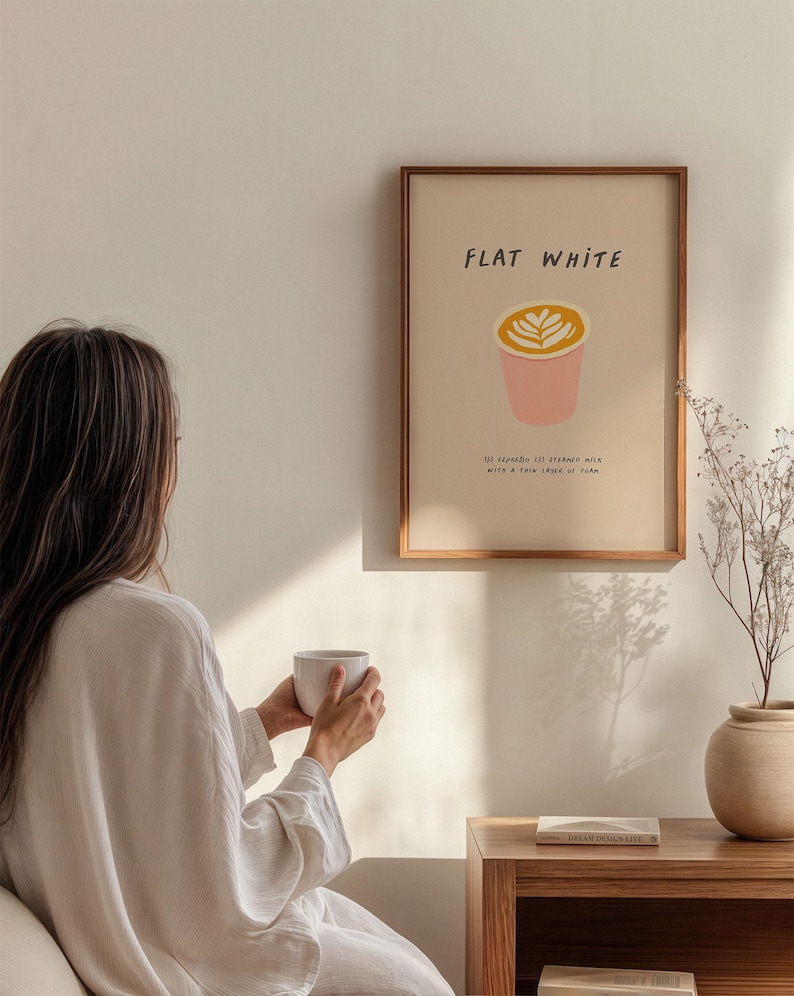 May include: A framed print with the text "FLAT WHITE" and a stylized illustration of a coffee cup with a latte art design. The text below the illustration reads "113 degrees espresso strained with a thin layer of foam."