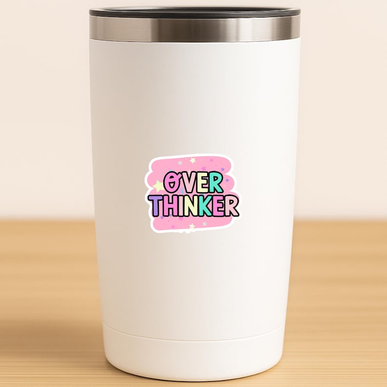 May include: A white stainless steel tumbler with a metallic rim featuring a central sticker. The sticker has a pink background with small stars and the text OVER THINKER in multi-colored, bold, outlined letters with a black border.
