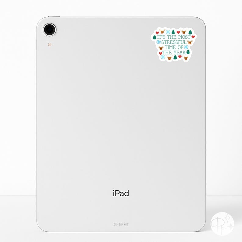 May include: A white iPad with a sticker that reads "IT'S THE MOST STRESSFUL TIME OF THE YEAR" in teal and red. The sticker features Christmas-themed icons like snowflakes, hearts, and reindeer.