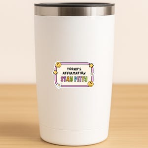 May include: A white stainless steel tumbler with a sticker that reads "TODAY'S AFFIRMATION STAY PETTY" in a colorful, retro design. The sticker features a purple border, yellow stars, smiley faces, and flowers.