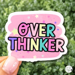 May include: A rectangular sticker with a pink background featuring scattered yellow, blue, and purple stars. The text OVER THINKER is printed in large, bold, multi-colored letters with a thick black outline against the pink star-filled backdrop.