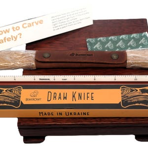 May include: A draw knife set with a wooden handle, leather sheath, and a ruler. The packaging includes the text "DRAW KNIFE" and "MADE IN UKRAINE". A card with the text "How to Carve Safely?" is also included.