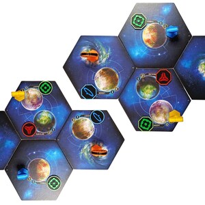 May include: A set of hexagonal board game tiles featuring space-themed illustrations of planets, nebulae, and stars. The tiles are arranged in two clusters and include various small plastic markers in red, blue, yellow, and green colors.
