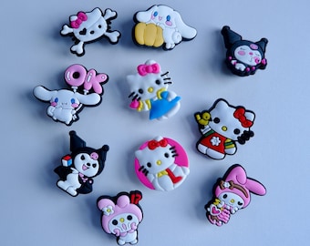 May include: A selection of colourful cartoon character charms, including Hello Kitty, Kuromi, and Cinnamoroll. The charms feature various designs with bows, outfits, and accessories. The charms are made of a rubbery material.