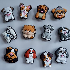 May include: Twelve colourful dog-themed shoe charms are displayed. The charms depict different dog breeds, such as a pug, a corgi, and a shih tzu. Each charm is made of a rubbery material and has a detailed, cartoon-like design.