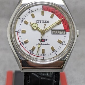 Puede incluir: Un reloj de pulsera autom&aacute;tico Citizen vintage con esfera blanca, agujas doradas y un acento rojo y blanco. La correa de cuero negro complementa la esfera, que muestra el d&iacute;a. La esfera incluye las palabras "Citizen" y "Automatic".