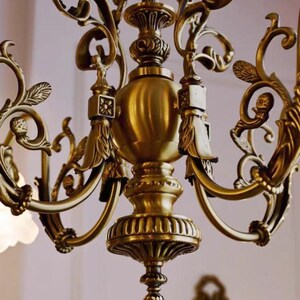 May include: A gold-toned chandelier with ornate, scrolled arms and a central, bulbous, decorative element. The chandelier has a classic, elegant design.
