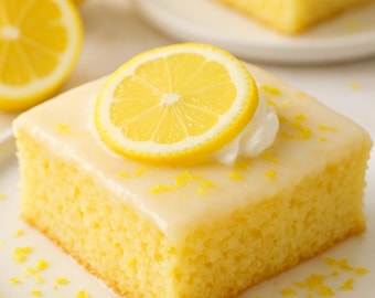 May include: A square slice of lemon cake on a white plate, topped with a lemon glaze, a lemon slice, and a dollop of whipped cream. Yellow lemon zest is sprinkled around the cake. A whole lemon and a lemon half are in the background.