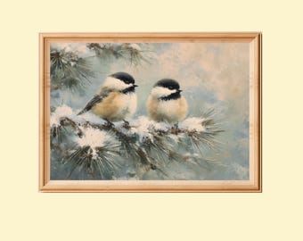 May include: A framed painting showing two small birds with black caps and white and tan bodies perched on a snow-covered pine branch. The background is a soft, muted blue and white winter scene. The frame is made of light-coloured wood.