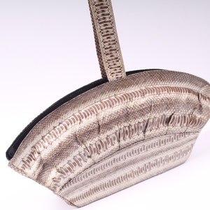 May include: A light brown snakeskin handbag with a curved shape and a matching snakeskin strap.