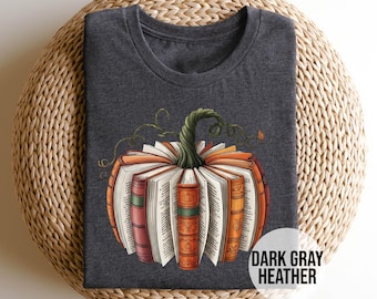 May include: Dark gray heather t-shirt featuring a pumpkin design made of books. The pumpkin has an orange and brown color scheme with a green stem and vines. The text "DARK GRAY HEATHER" is in a white circle.