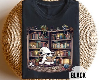 Könnte beinhalten: Schwarzes T-Shirt mit einem Cartoon-Geist, der in einer Bibliothek ein Buch liest. Der Geist trägt einen weißen Zaubererhut und sitzt vor einem Bücherregal voller Bücher. Das Wort "BLACK" ist unten rechts in Weiß aufgedruckt.