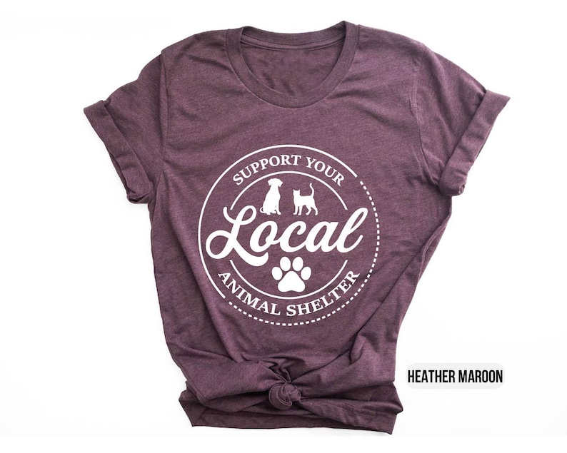 May include: Heather maroon t-shirt with a white circle graphic that says "Support Your Local Animal Shelter" with a paw print and silhouettes of a dog and cat.